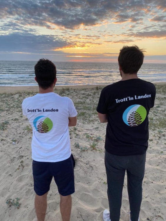 2 hommes avec un tee-shirt Trott'in Landes regardent le coucher de soleil