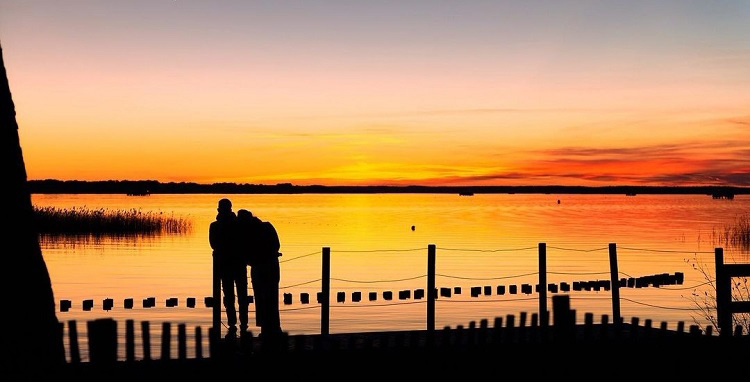 Couple face au coucher du soleil au lac de Biscarrosse Parentis dans les Landes