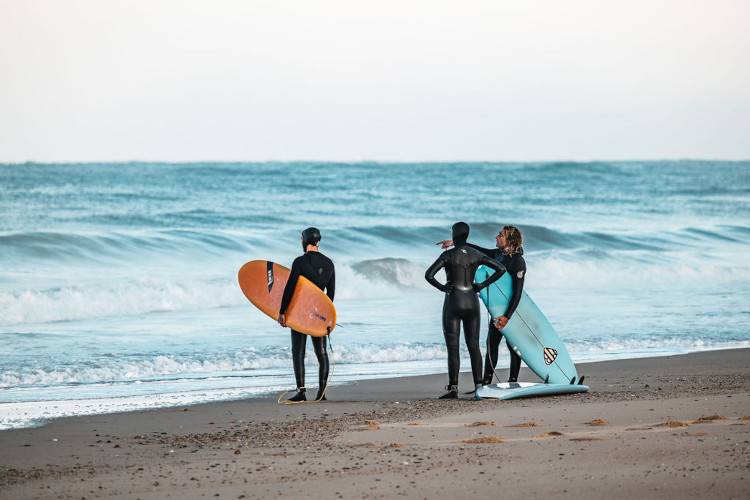 Raphael de Surf Guides montre l'océean à deux surfeurs