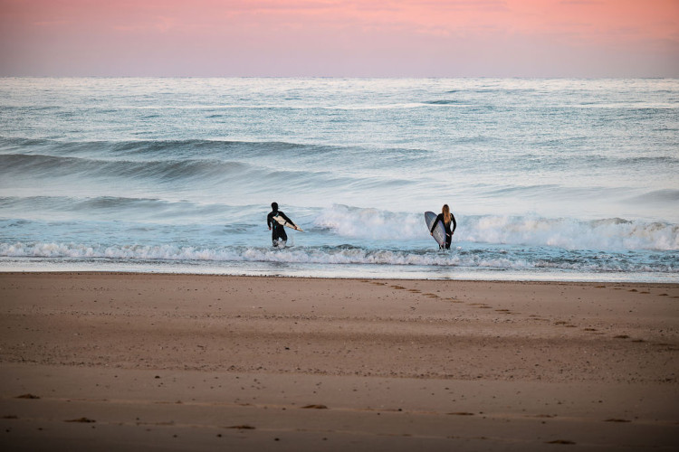 deux surfeurs partant surfer au lever du soleil